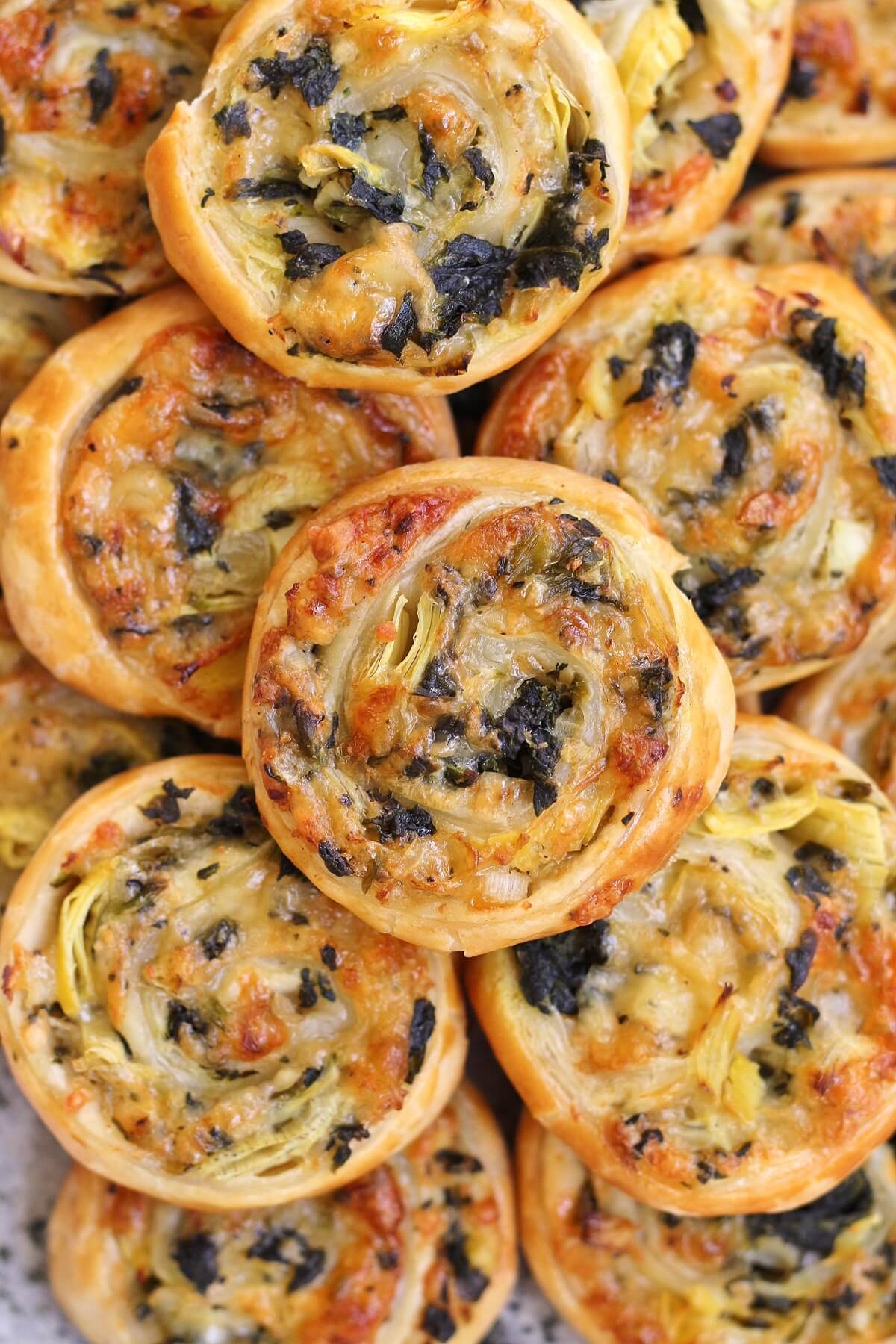 Closeup view of a pile of spinach and artichoke puff pastry swirls.