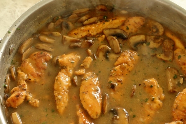 closeup of chicken marsala made with chicken tenders and mushrooms in a metal pan
