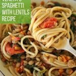 Spaghetti with lentils, roasted tomatoes, and spinach with a fork scooping some up