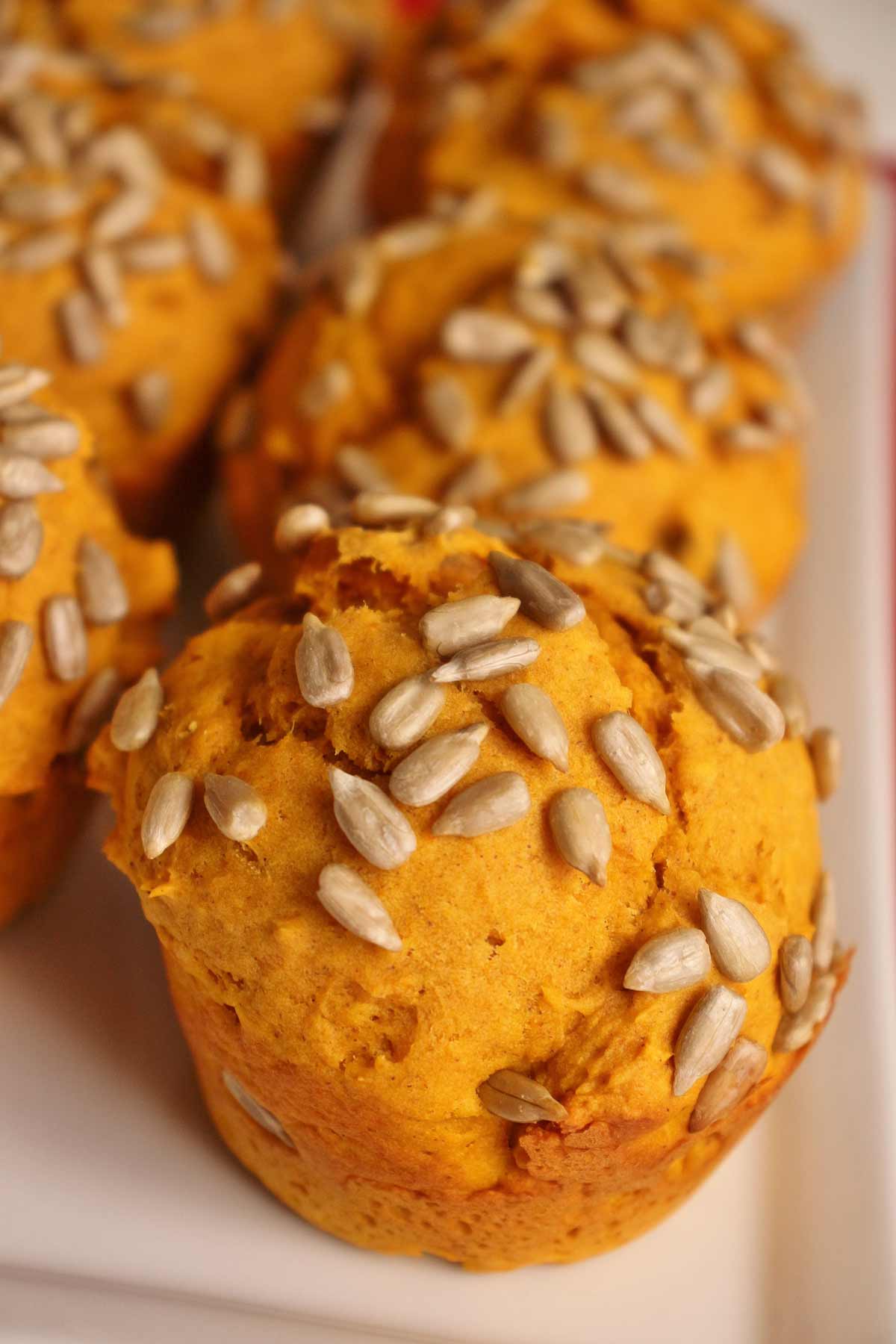 Closeup of bright orange pumpkin muffins topped with sunflower seeds.