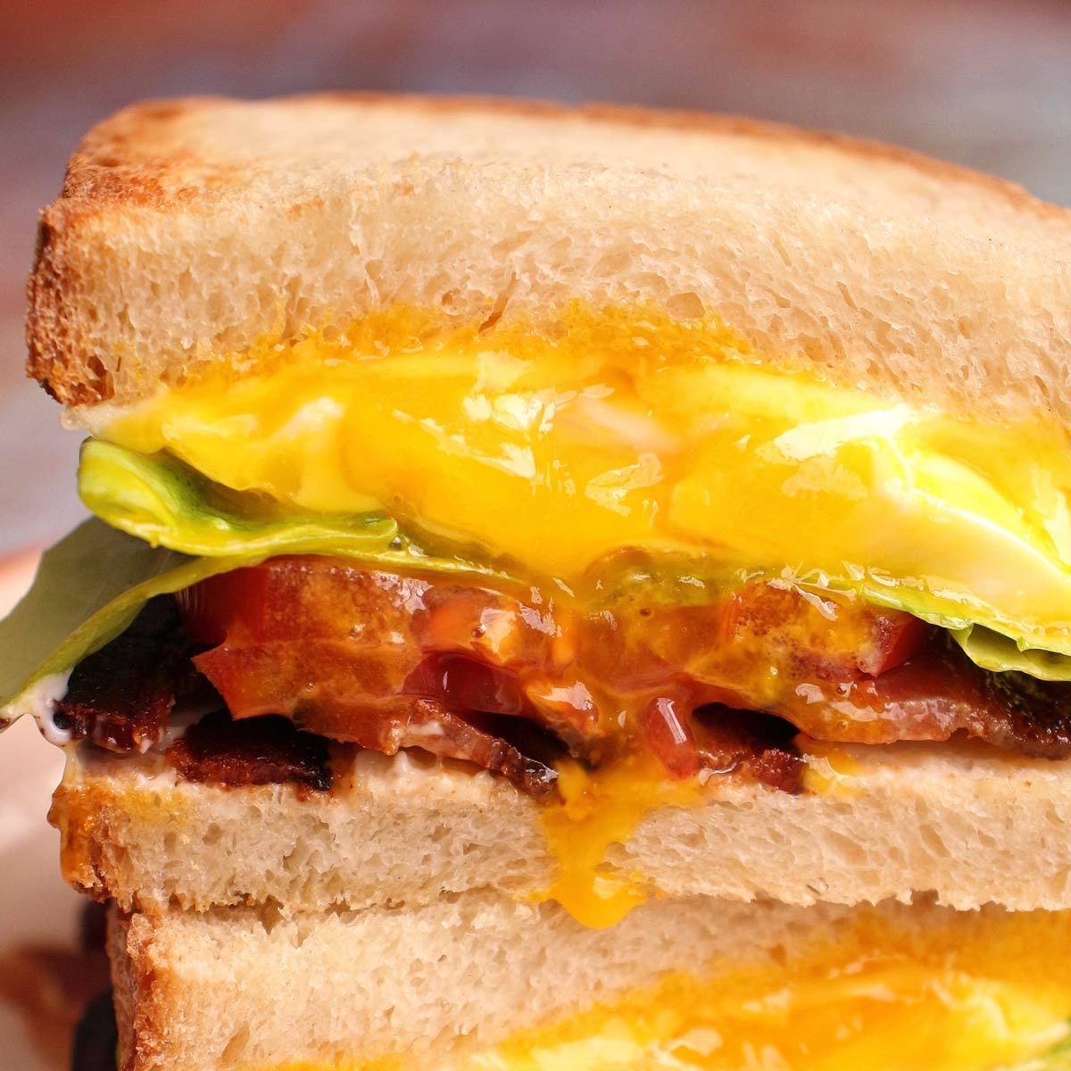 Closeup of Spanglish sandwich cross-section with runny egg yolk dripping down the front.