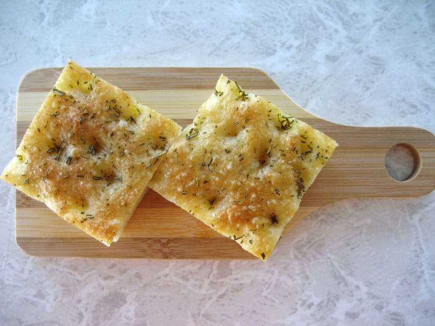 overhead view of two squares of focaccia bread on a small wooden board