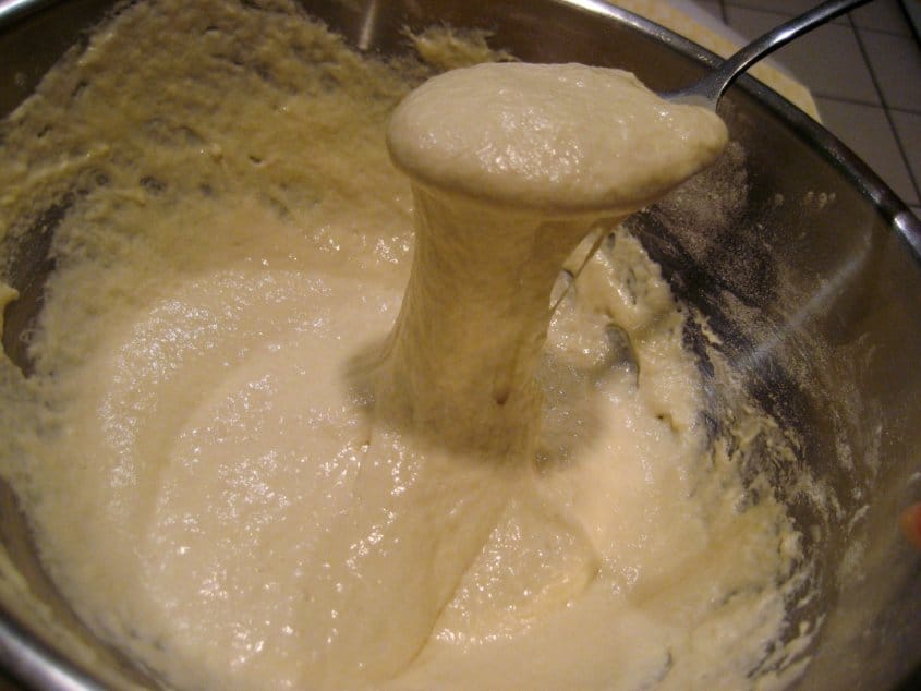 a spoon scooping up bread starter out of a mixing bowl