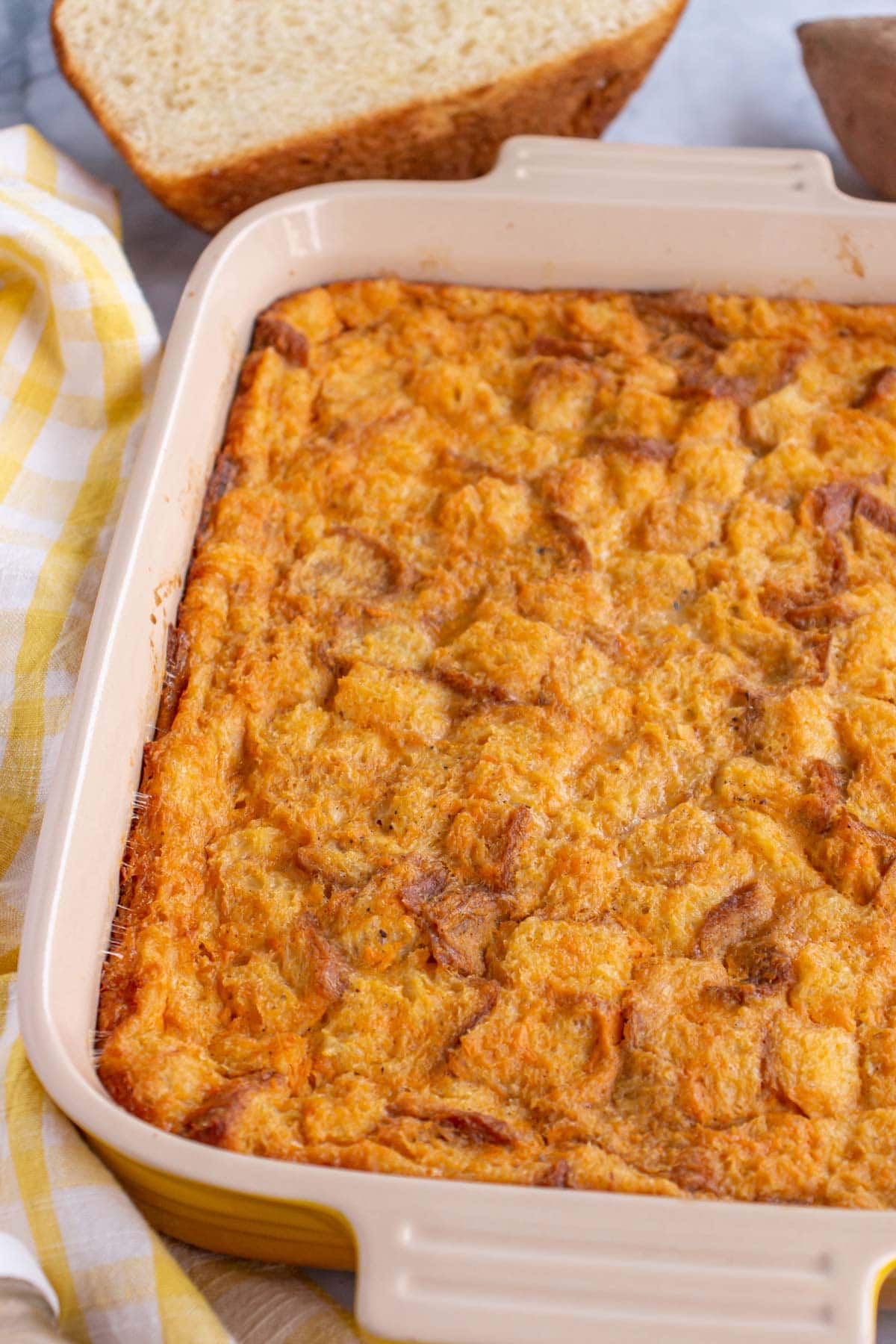 Orange-hued sweet potato bread pudding baked in a rectangular ceramic baking dish.