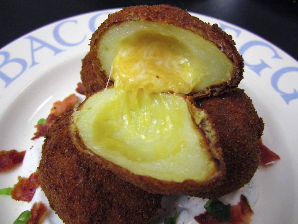 A fried potato stuffed with cheese, cut open to show the melted cheese inside.