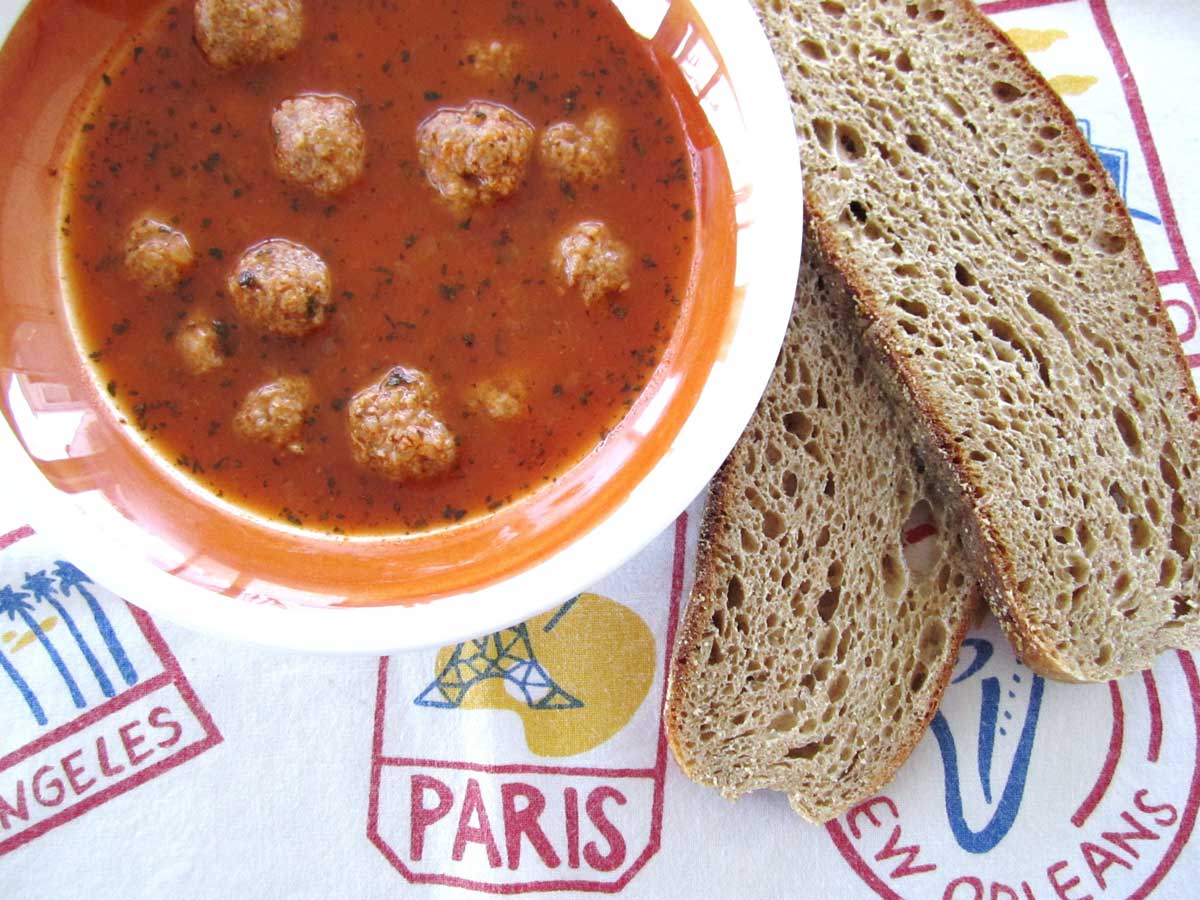 Closeup of a bowl of Armenian meatball soup with wheat toast next to the bowl.