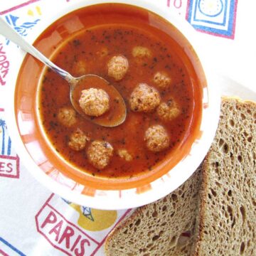 A bowl of Armenian meatball soup with sliced wheat toast next to the bowl.