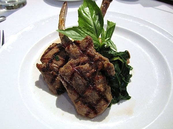 two grilled lamb chops with cooked Swiss chard on a white plate