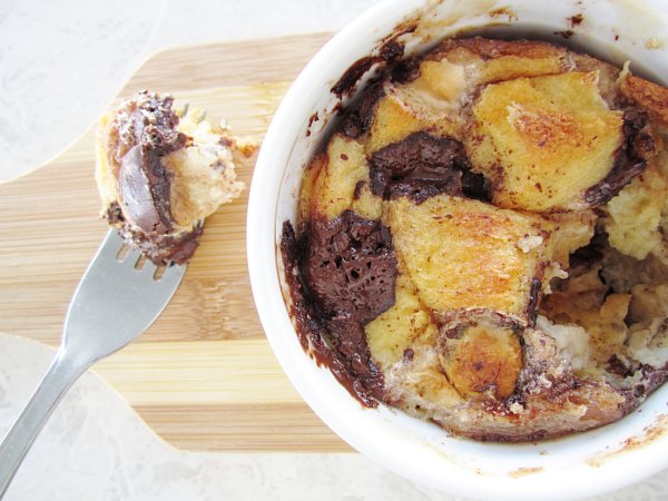 overhead view of a half eaten ramekin of s\'mores bread pudding with chocolate and marshmallows