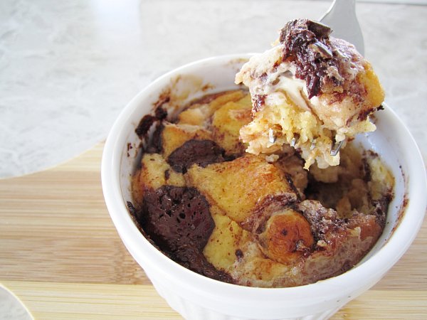 a closeup of a forkful of s\'mores bread pudding with melted chocolate and marshmallows