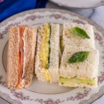 Closeup of an assortment of tea sandwiches on a floral china plate.
