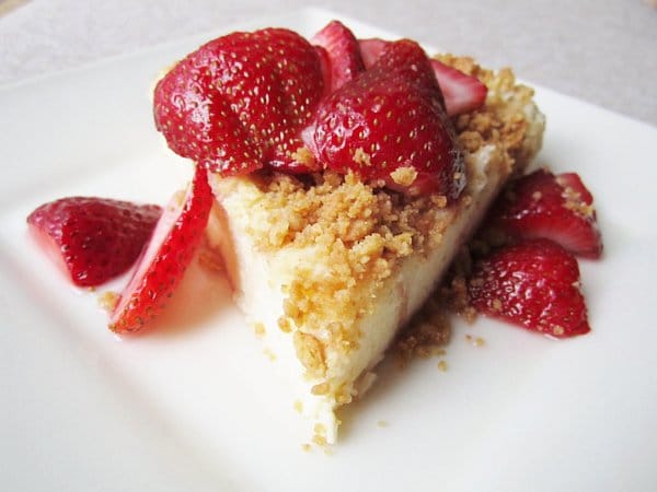 a wedge of bread pudding that resembles cake topped with crumbs and strawberry slices