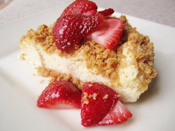 a wedge of crumb topped bread pudding with sliced strawberries over the top and sides