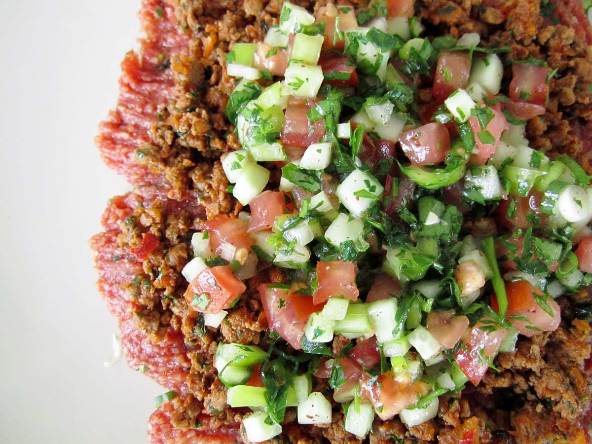 Chi kofte garnished with gheyma (ground beef) and salad.