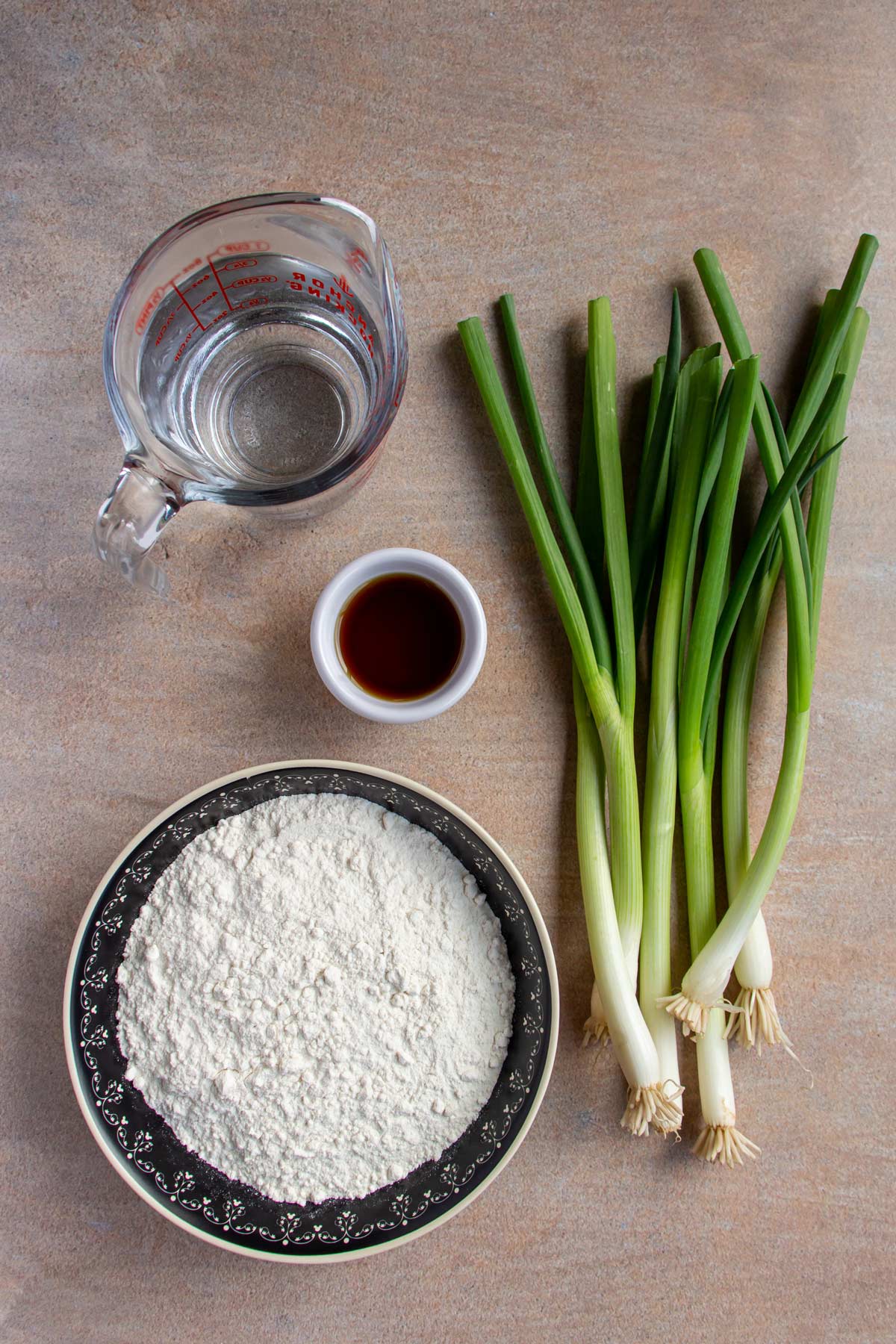 Ingredients for scallion pancakes on a beige background.