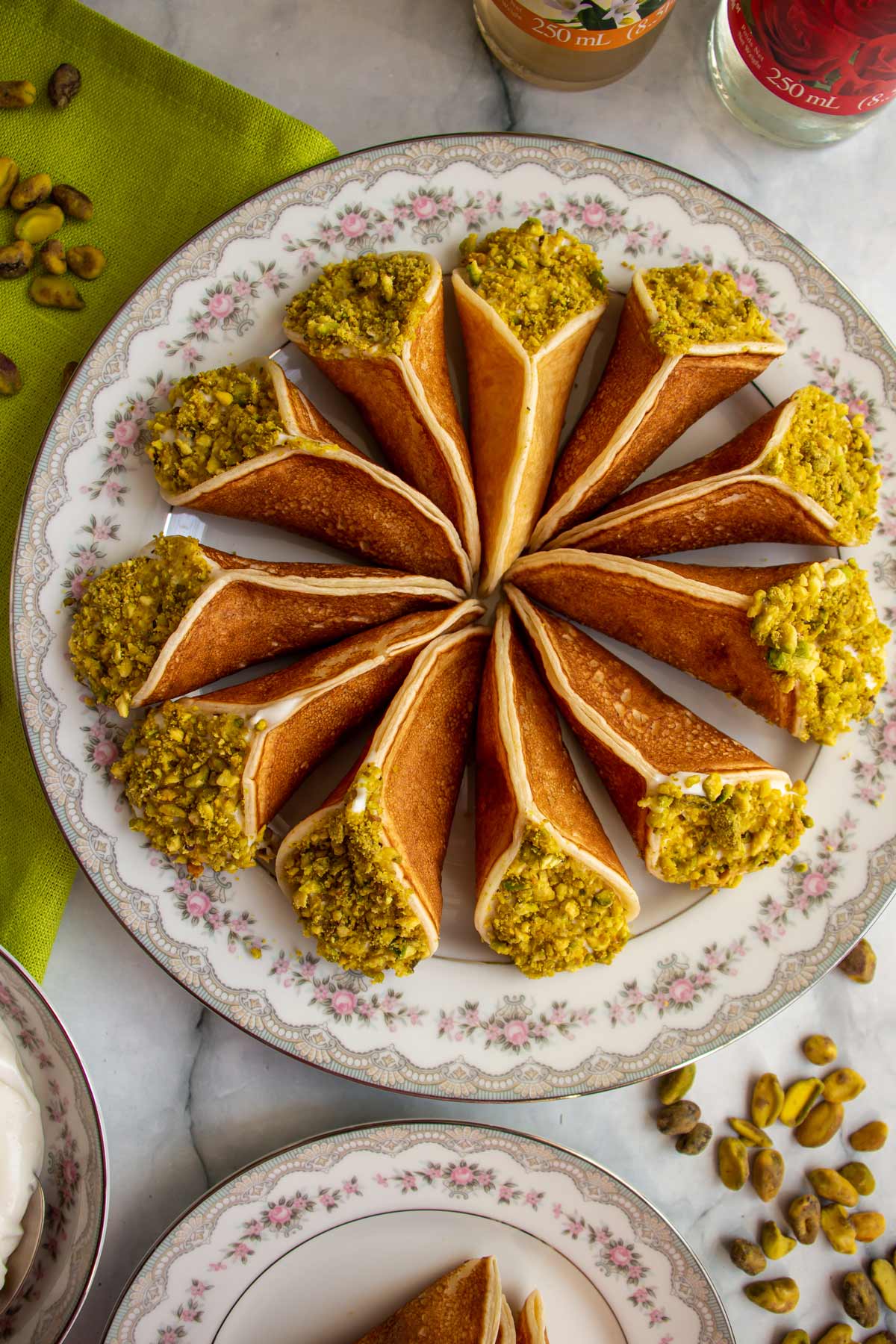 Closeup of qatayef asafiri arranged in a spiral pattern on a round china plate.