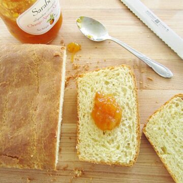 overhead view of a partially sliced loaf of brioche with orange jam on one slice