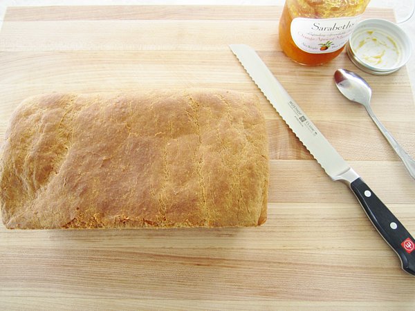 overhead view of a loaf of bread with a knife on a wooden board