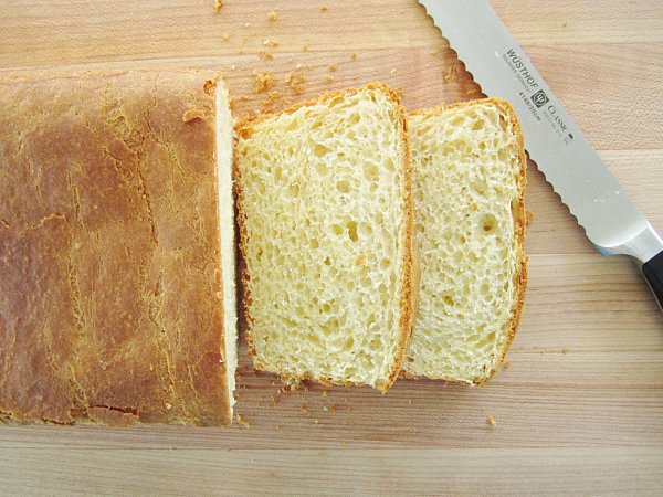 overhead view of a partially sliced loaf of brioche on a wooden board