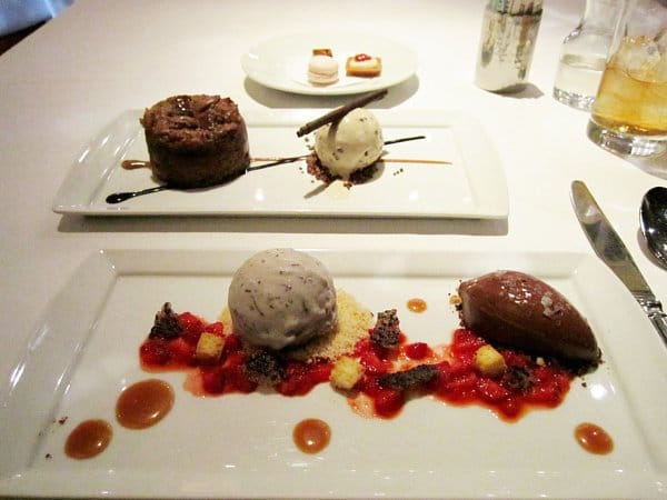 two plates of artistically plated desserts on a white tablecloth