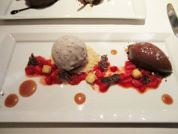 a plate of dessert with scoops of ice cream and chocolate mousse with strawberries