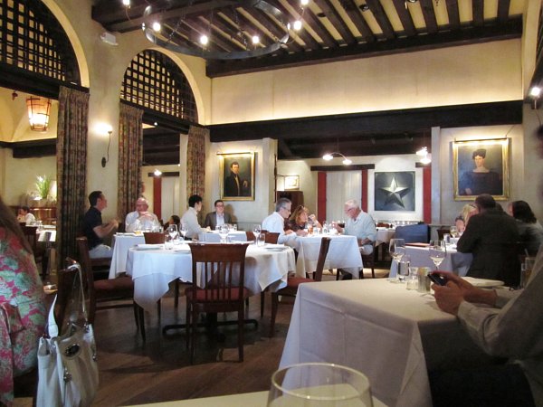 a restaurant dining room with dark wood ceiling beams and white tablecloths