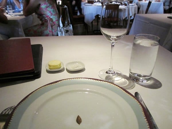 A table setting in a restaurant with a plate, utensils, and glasses on a white tablecloth