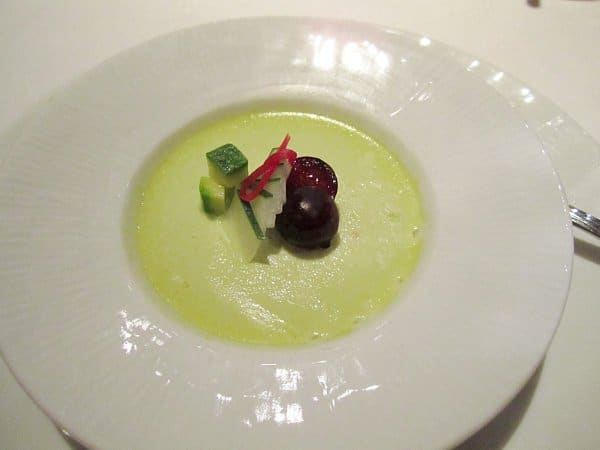 a bowl of light green custard topped with sliced zucchini