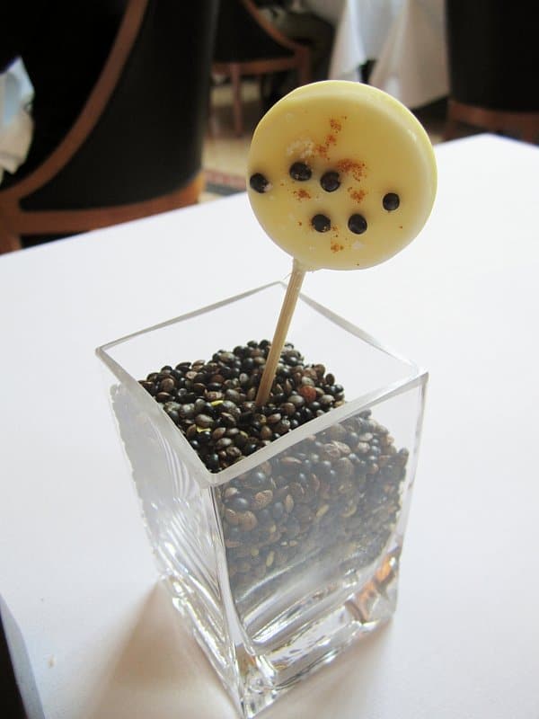 a white lollipop with black dots sticking out of a glass vase