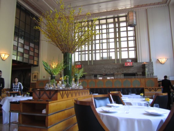 an elegant restaurant dining room with very tall ceilings and lots of natural light