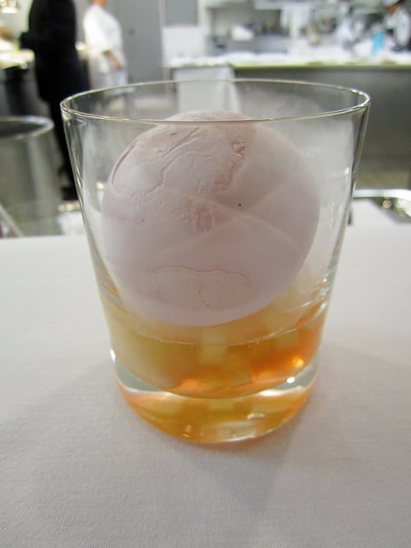 a scoop of ice cream in a glass over a tan liquid