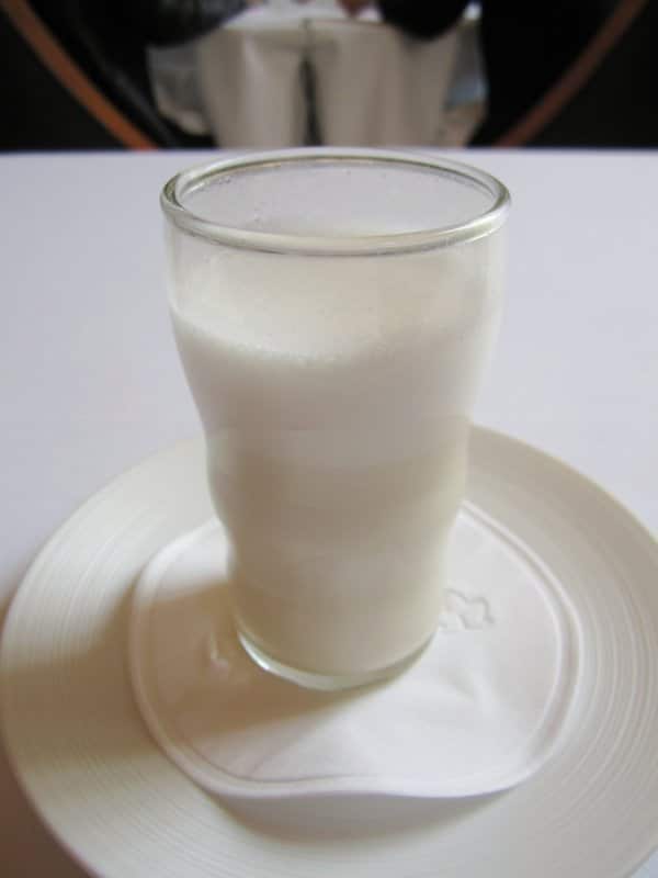 A glass filled with a white drink on a white table