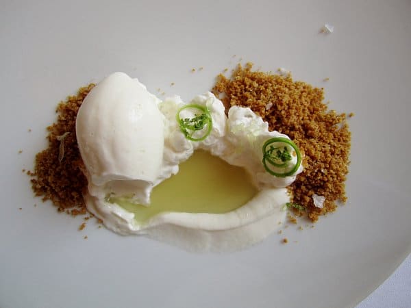 dessert with white ice cream, whipped cream, crumbs and a pool of liquid in the middle
