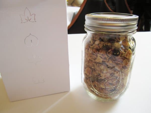 a jar of granola next to a white bag with silver graphics on it