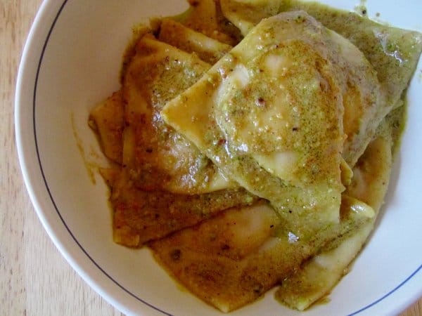 overhead view of a bowl of triangular tortelli with green pistachio pesto