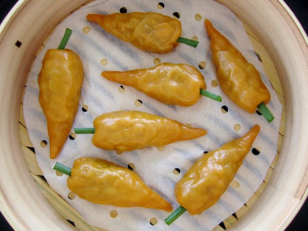 overhead view of carrot shaped dumplings in a bamboo steamer basket