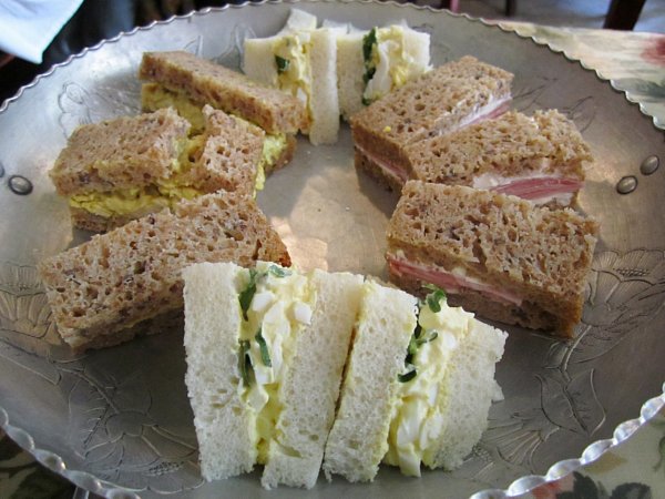 A closeup of tea sandwiches arranged in a circle on a metal surface