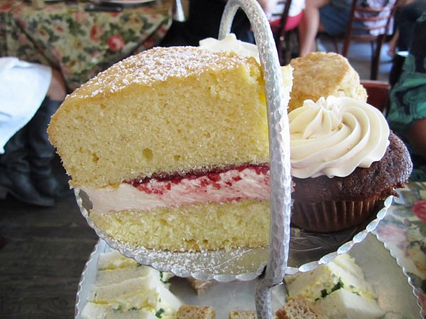 a closeup of a large slice of Victoria Sandwich sponge cake filled with cream and jam