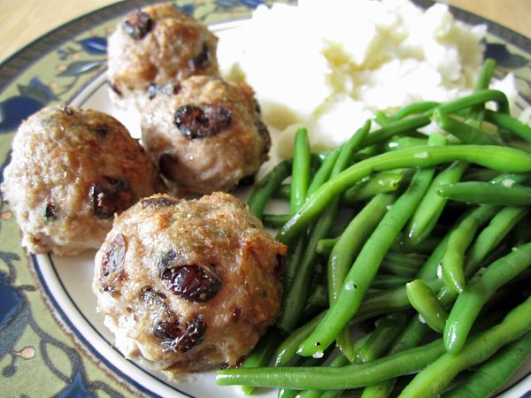 a closeup of meatballs and green beans on a plate