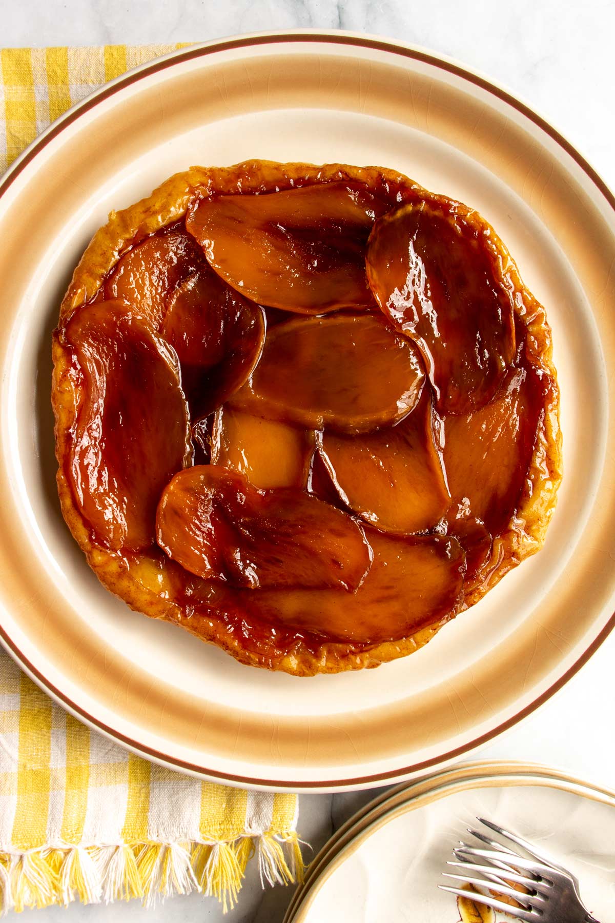 A caramelized layer of sliced mangos on a round tart served on a platter.
