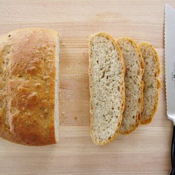 overhead view of a partially sliced loaf of bread on a wooden board