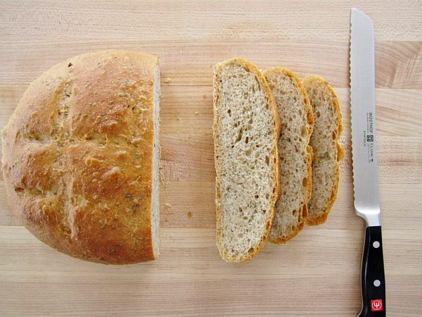 overhead view of a partially sliced loaf of bread on a wooden board