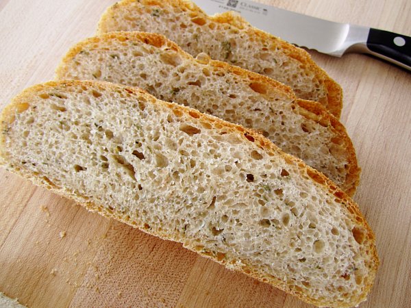 a closeup of three slices of fresh thyme bread on a wooden board