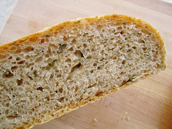 closeup of a cross section of fresh thyme bread on a wooden surface