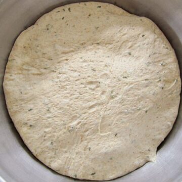 overhead view of bread dough in a metal mixing bowl