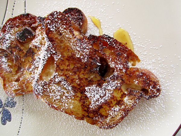 overhead closeup of a plate of French toast topped with maple syrup and powdered sugar