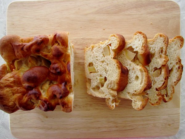 overhead view of a partially sliced loaf of apple cinnamon bread on a wooden board