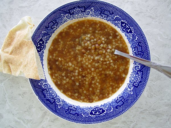 overhead view of lentil soup in a wide bowl with blue and white edges