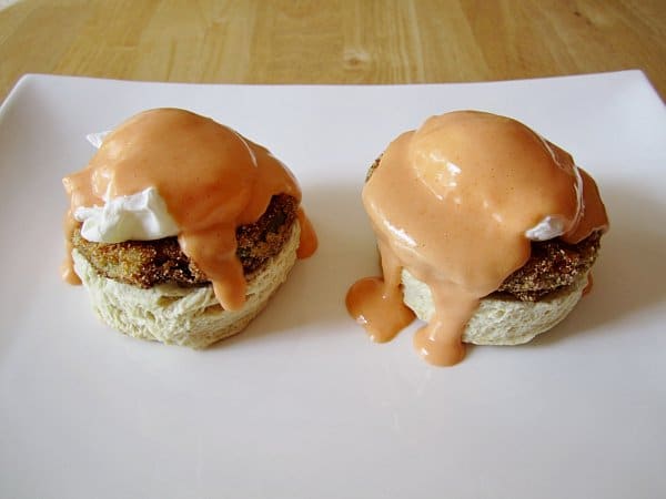 side view of two biscuits topped with fried green tomato, poached eggs, and Buffalo Hollandaise sauce