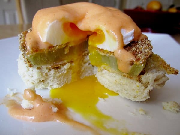 A closeup of a half-eaten Eggs Benedict with fried green tomato and Buffalo Hollandaise sauce